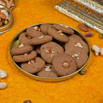 Millet cookies with nuts in a metal tray on an orange surface