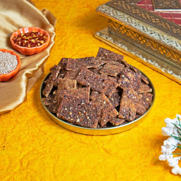 Millet crackers in a metal tray on a yellow textured surface with decorative elements.