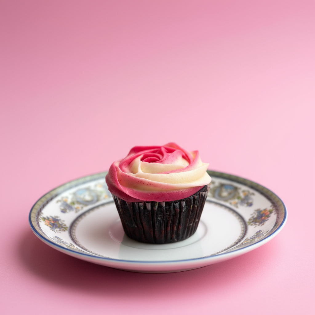 Cupcake with pink and white frosting on a decorative plate against a pink background