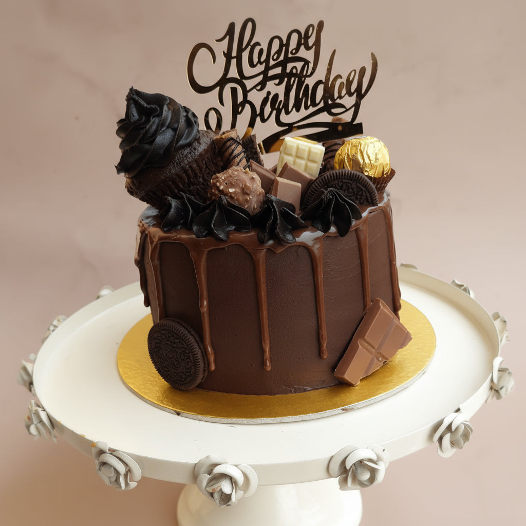 Chocolate birthday cake with decorative elements on a white cake stand.