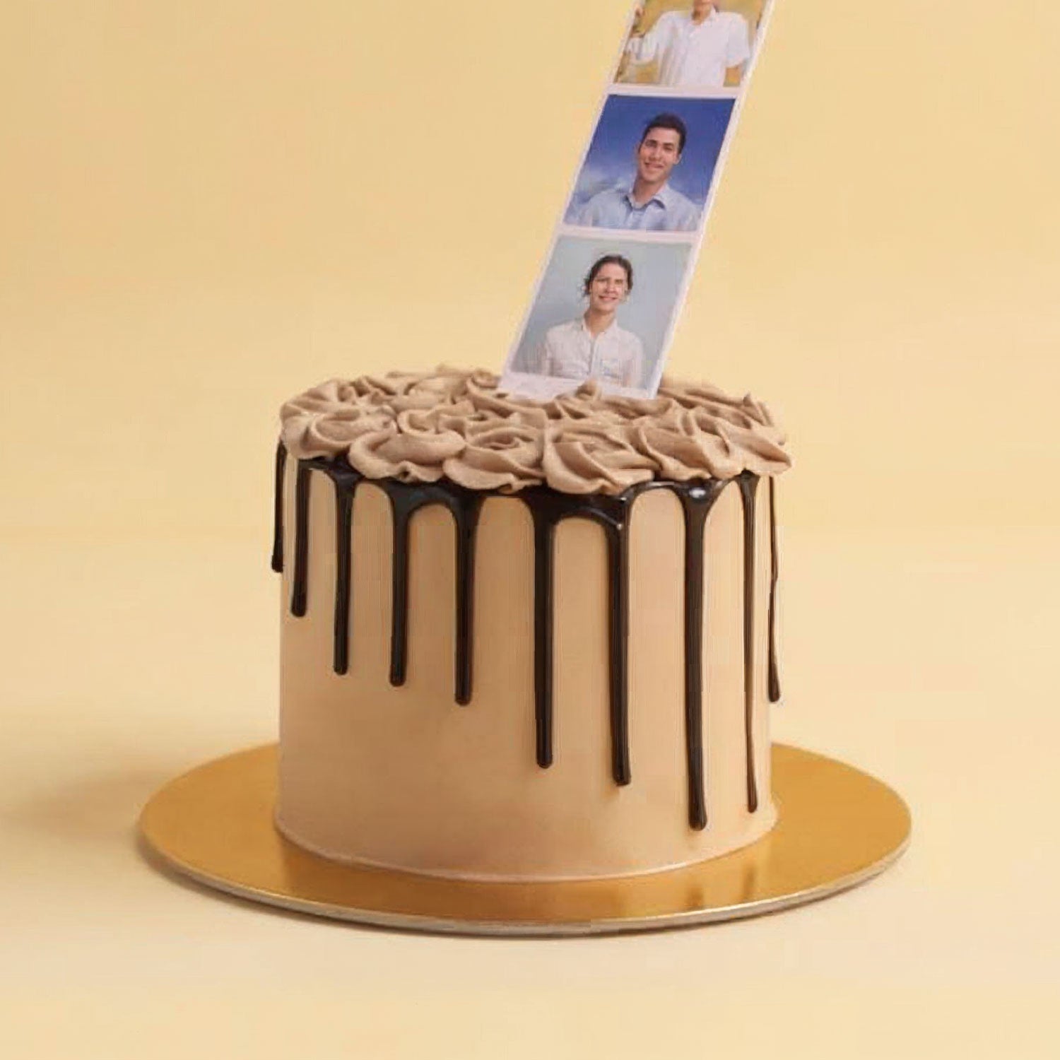 Beige cake with chocolate drizzle on a gold stand against a beige background