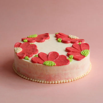 Decorative cake with red floral designs on a pink background