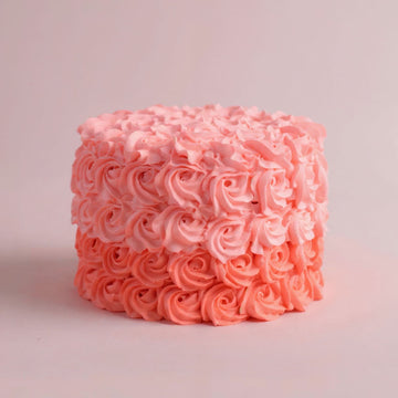 Pink frosted cake with intricate patterns on a light pink background