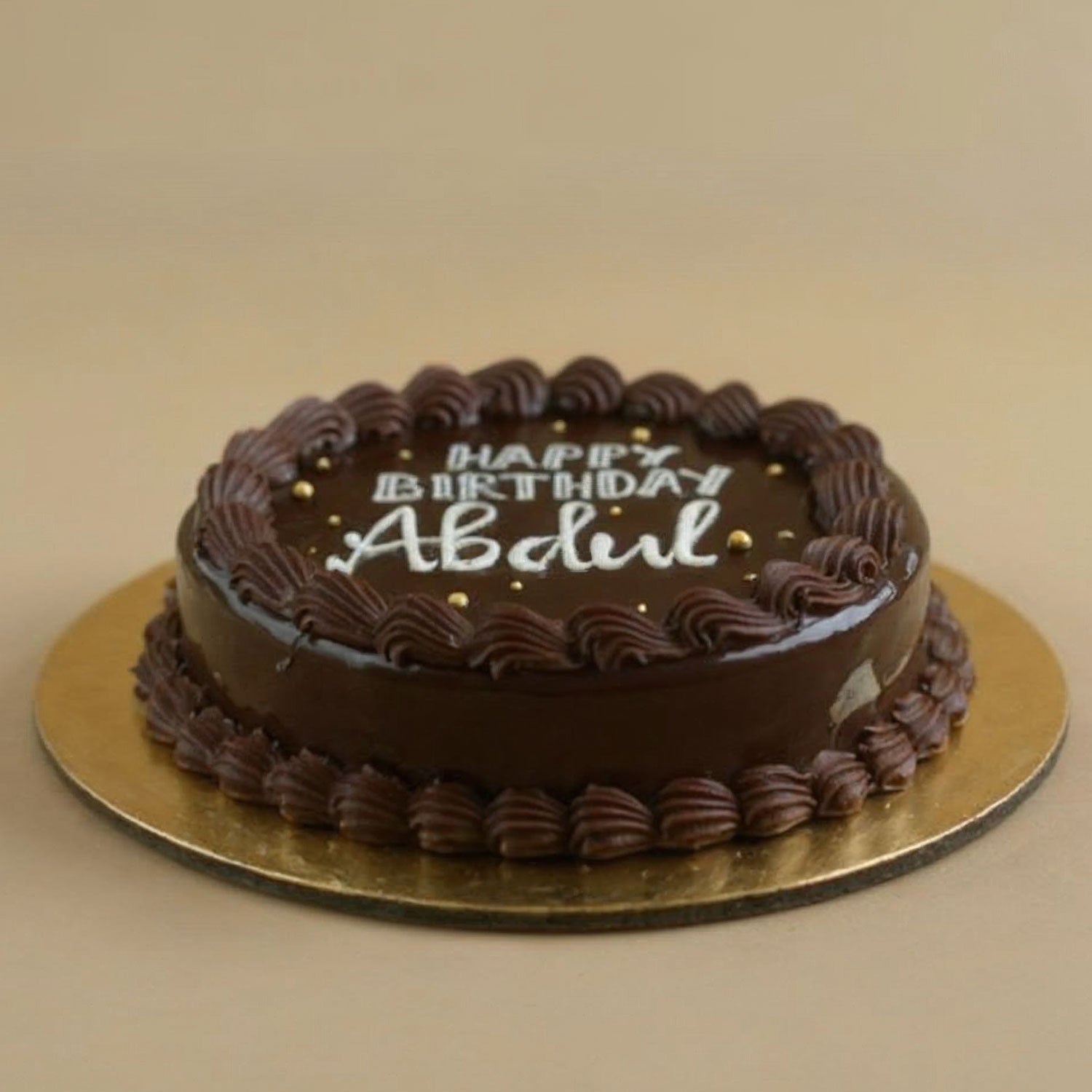 Chocolate birthday cake with 'Happy Birthday Abdul' text on a beige background