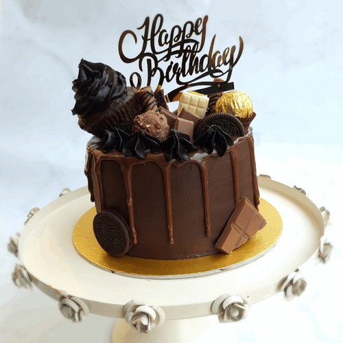 Choco-overload cake decorated with white, dark, and milk chocolates, and a cupcake. 