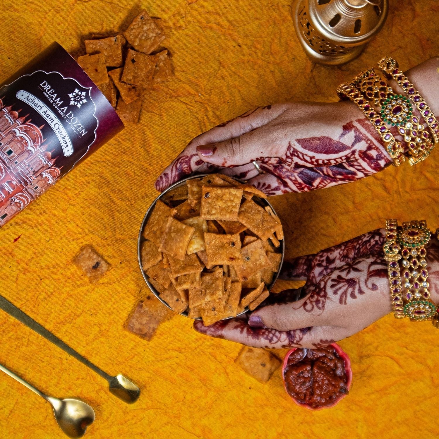 Person holding a container of crackers on a yellow surface with a Dreamland Tea box.