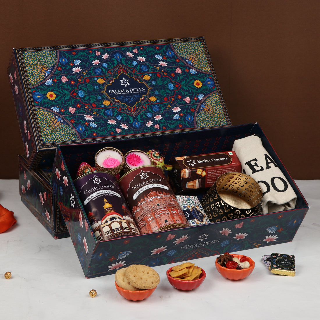 Gourmet gift box with various treats on a white surface against a brown background