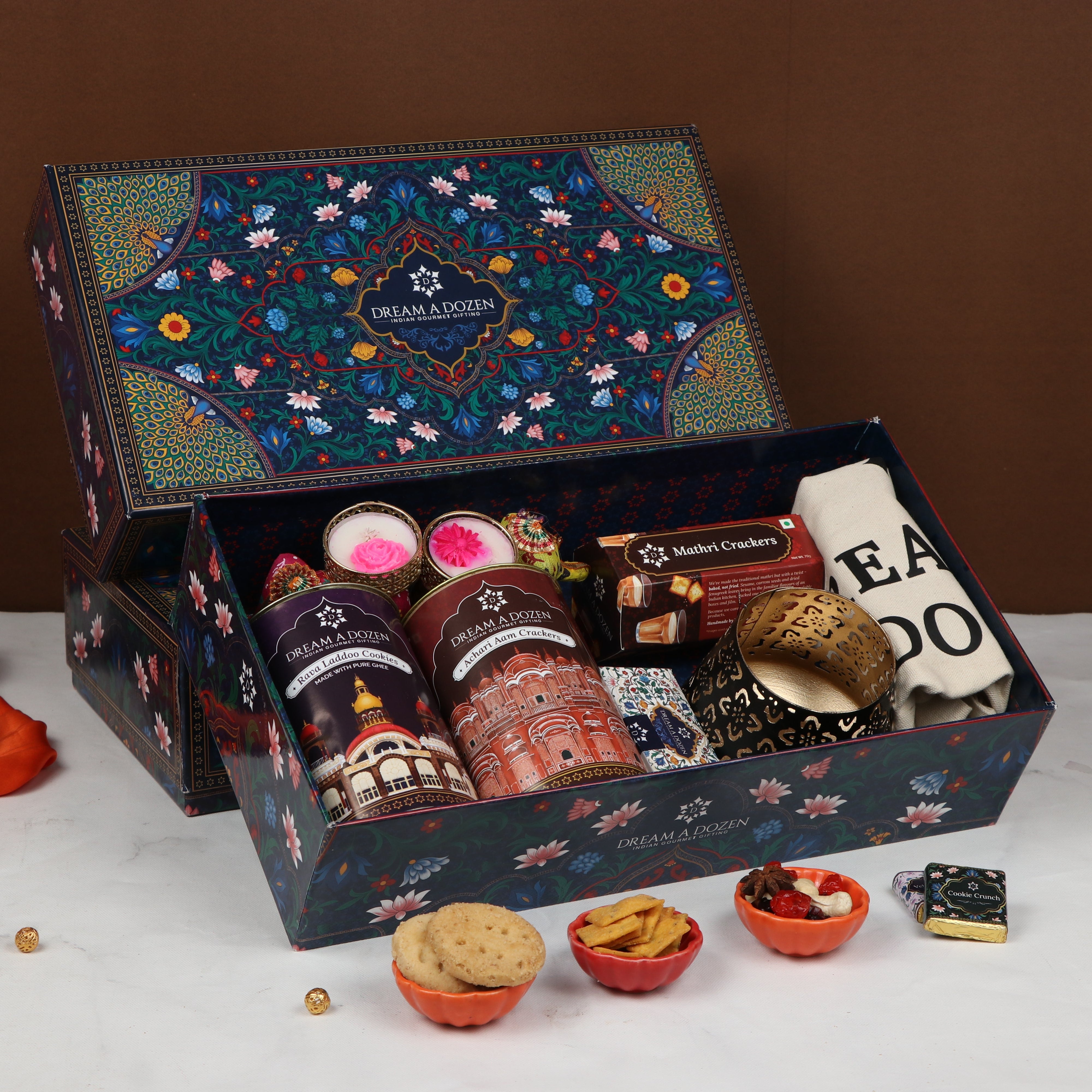 Gourmet gift box with various treats on a white surface against a brown background