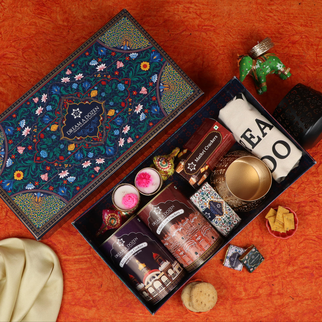 Gourmet gift box with various treats on a white surface against a brown background