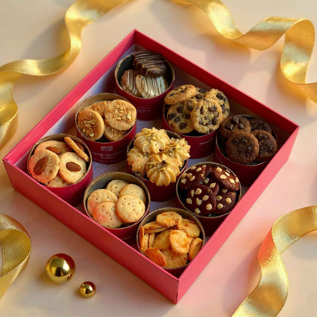 Assorted cookies in a red box with gold ribbons on a light background