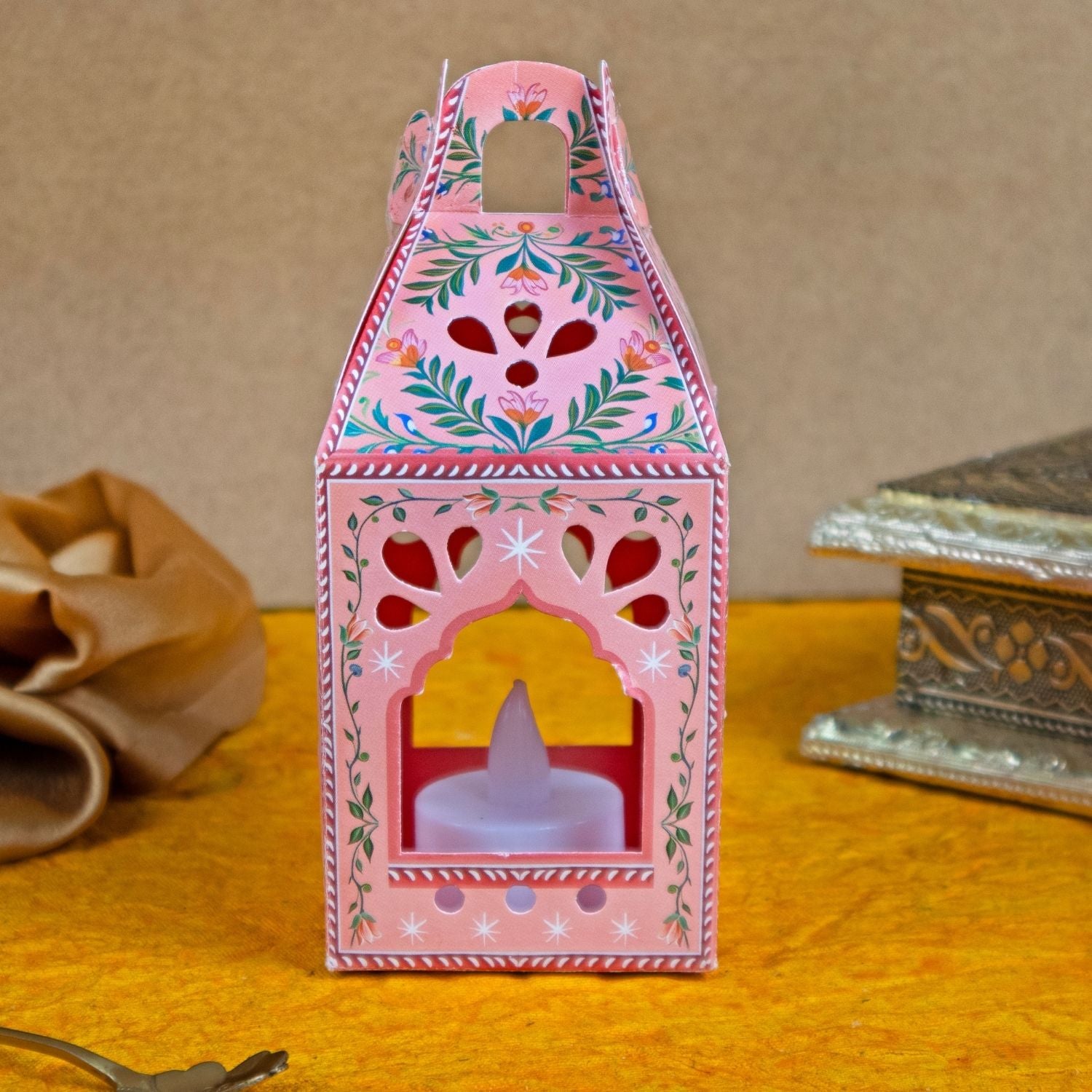 Decorative pink lantern with floral patterns on a yellow surface