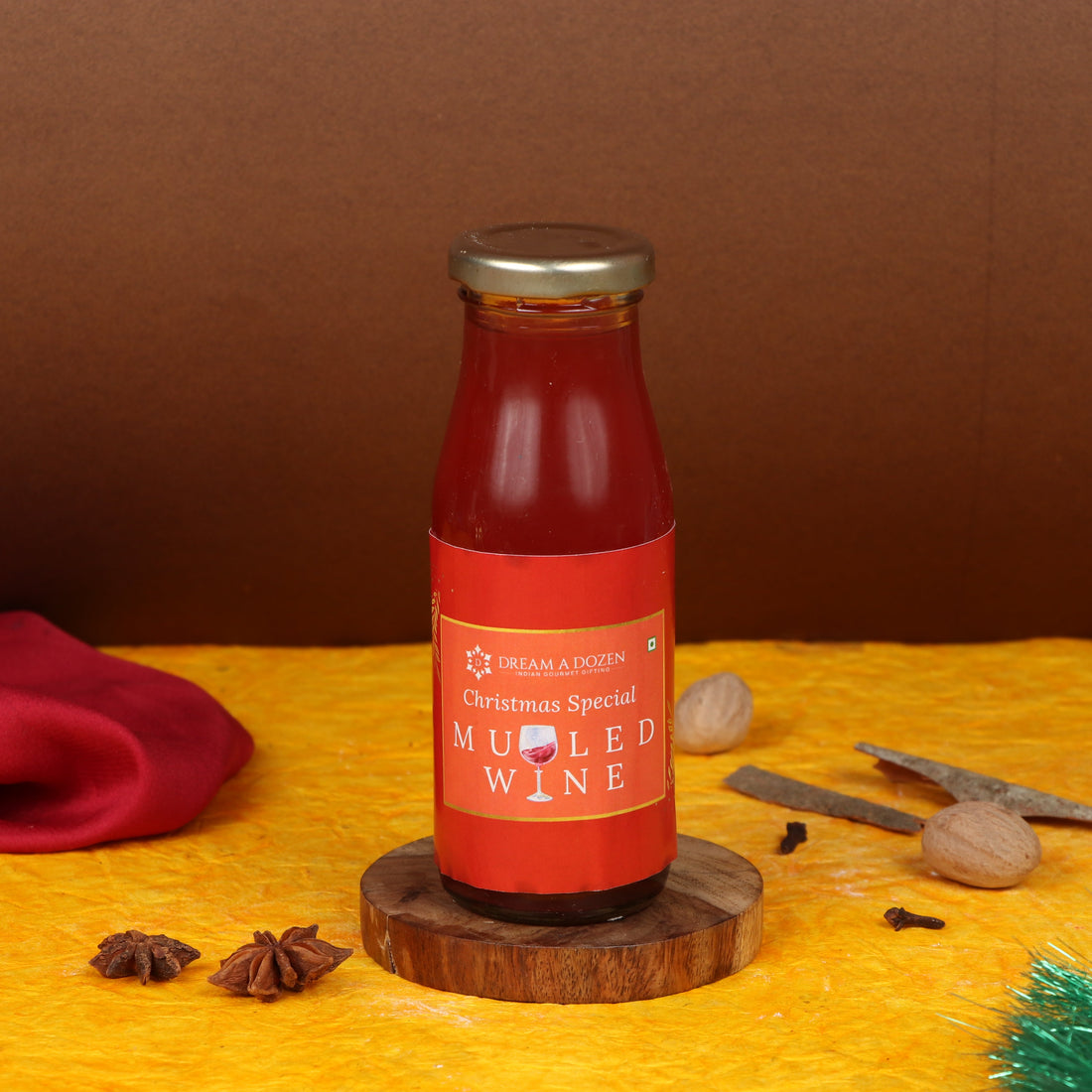 Bottle of mulled wine on a wooden stand with Christmas decorations on a yellow surface.