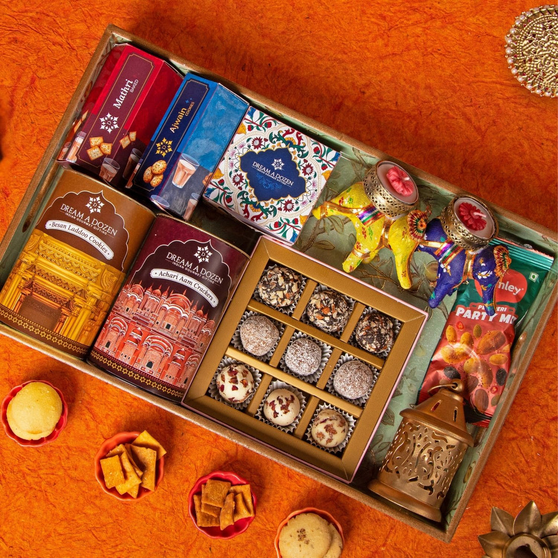 Assorted snacks and candies in a decorative box on an orange surface