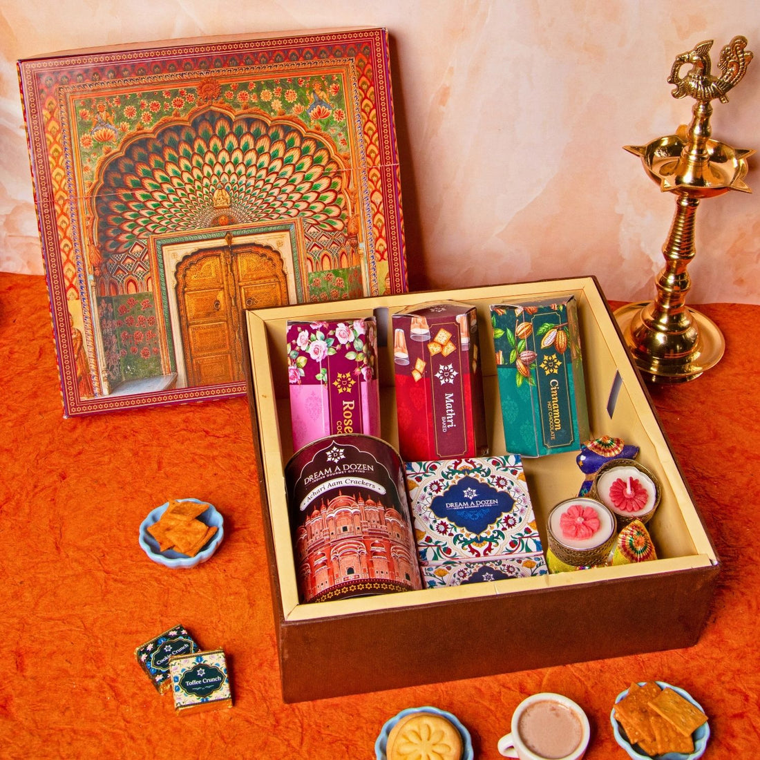 Assorted tea boxes in a decorative box with a traditional book and brass lamp on an orange surface.