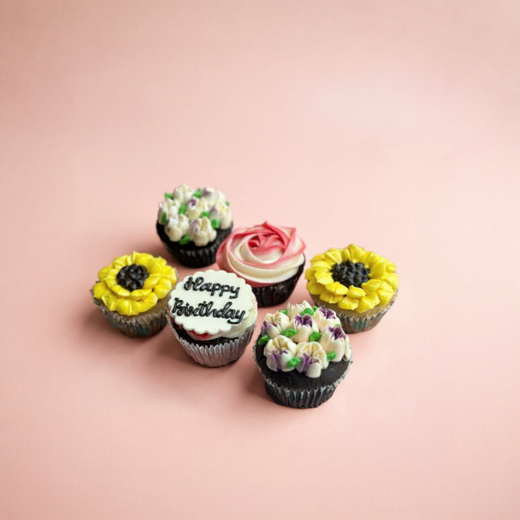 Colorful cupcakes with floral designs on a pink background