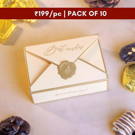 a close up top down shot of an elegant envelope style rectangular beige colored box with golden borders and a golden seal along with best wishes written in cursive gold above the seal 
priced at just ₹199 per piece it comes in a pack of 10 and is the perfect sweet treat for wedding gifts