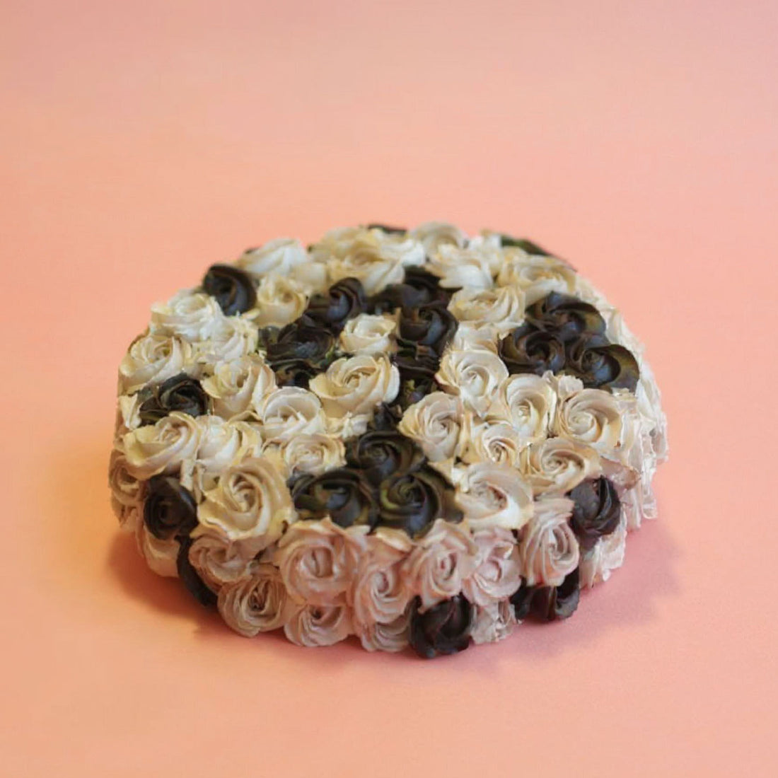 Decorative cake with black and white rose patterns on a pink background