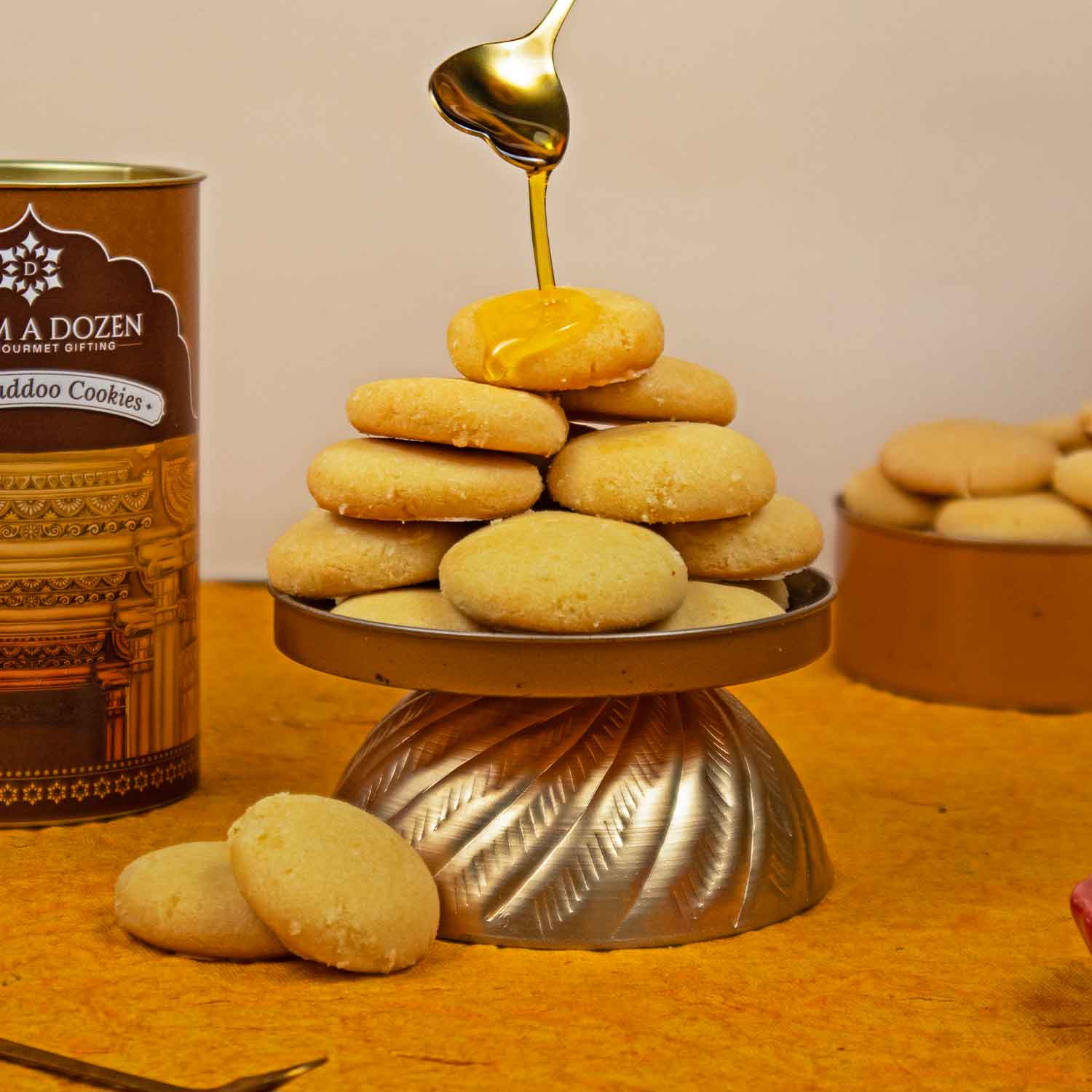 Cookies on a stand with honey being drizzled over them, next to a can of cookies.