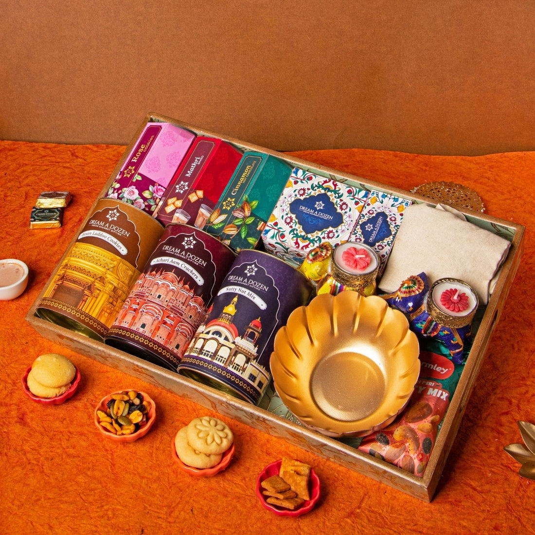 Assorted items including tea bags, a gold plate, and small containers on an orange surface.
