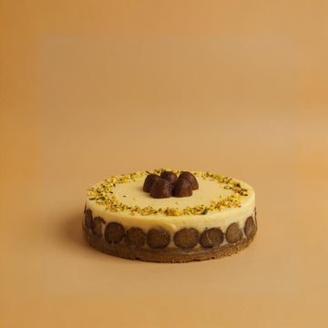 Small round cheesecake with white frosting and Gulab Jamun on a beige background