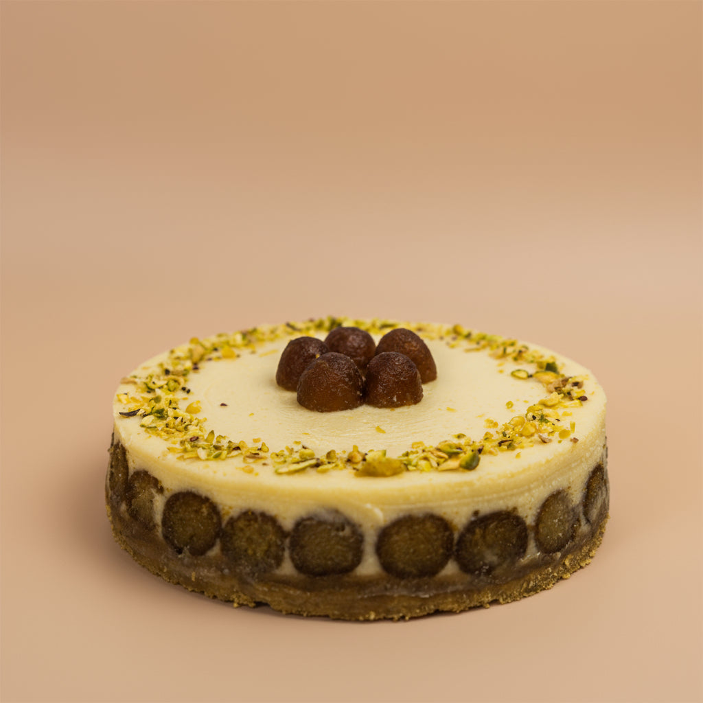 Round cake with white cream, chocolate balls, and green garnish on a beige background