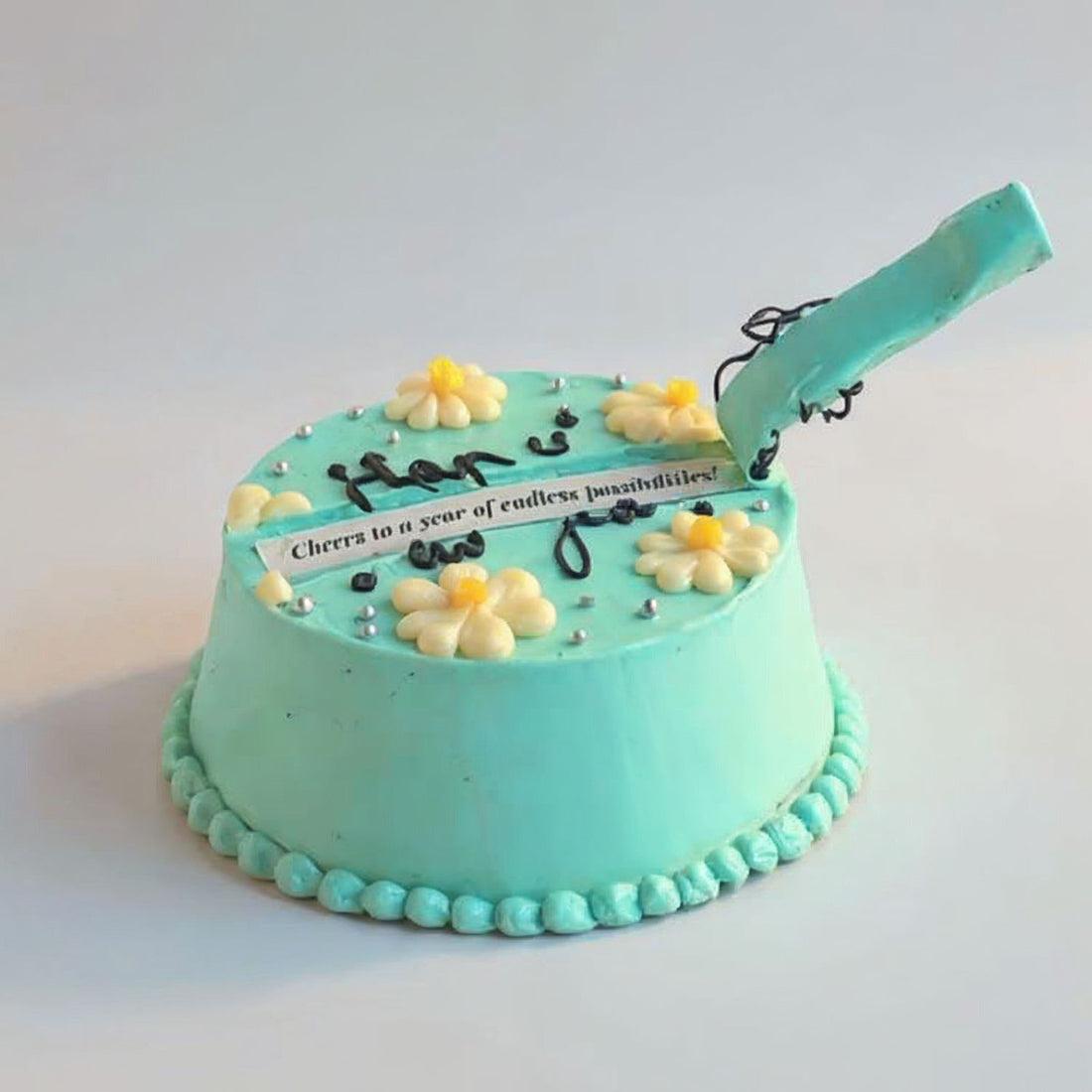 Turquoise cake with white flowers and a message on a white background