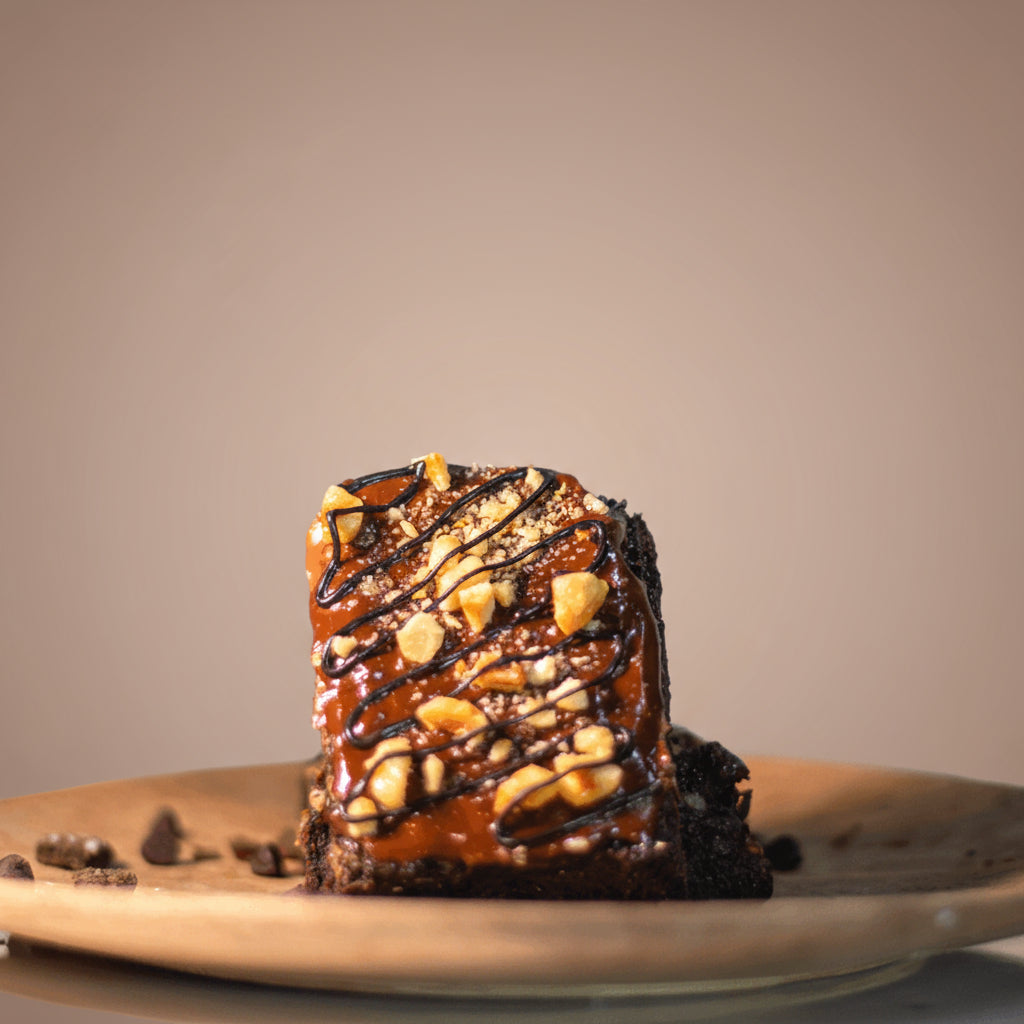 Nutella brownie with nuts on a wooden plate against a brown background