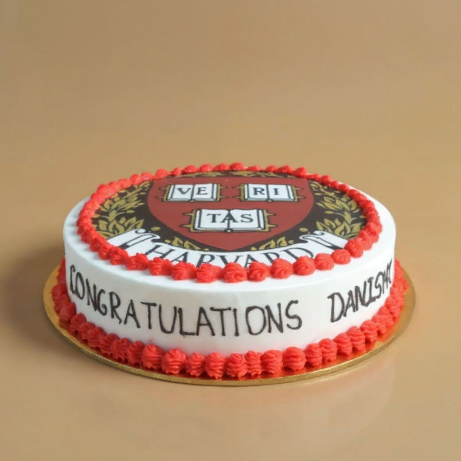 Round cake with Harvard University logo and 'Congratulations' text on a beige background