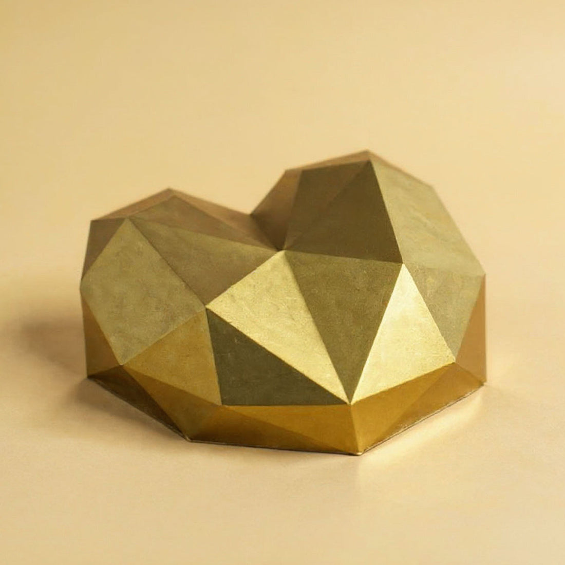 Geometric gold heart-shaped object on a beige background