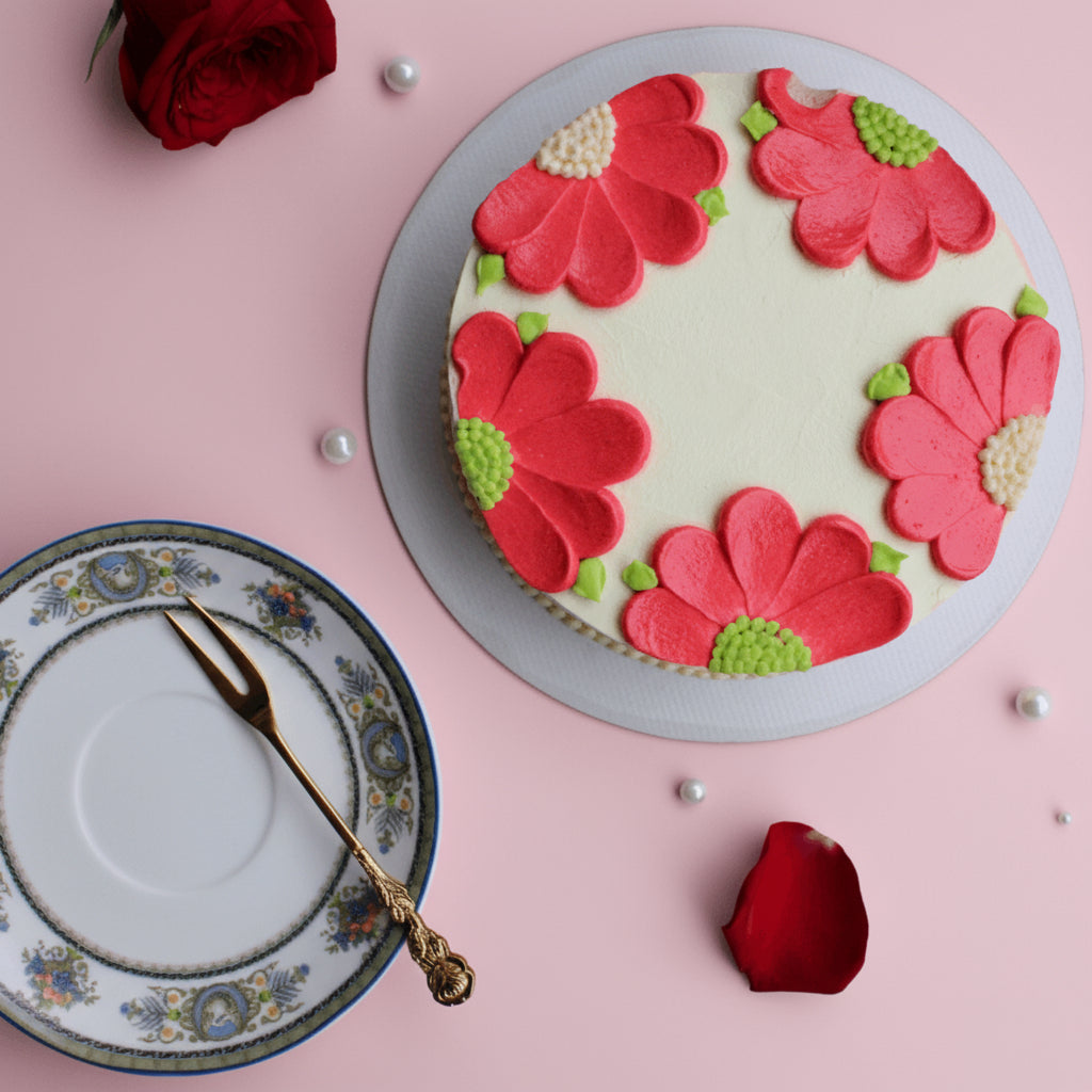Round cake with red floral decorations on a pink background