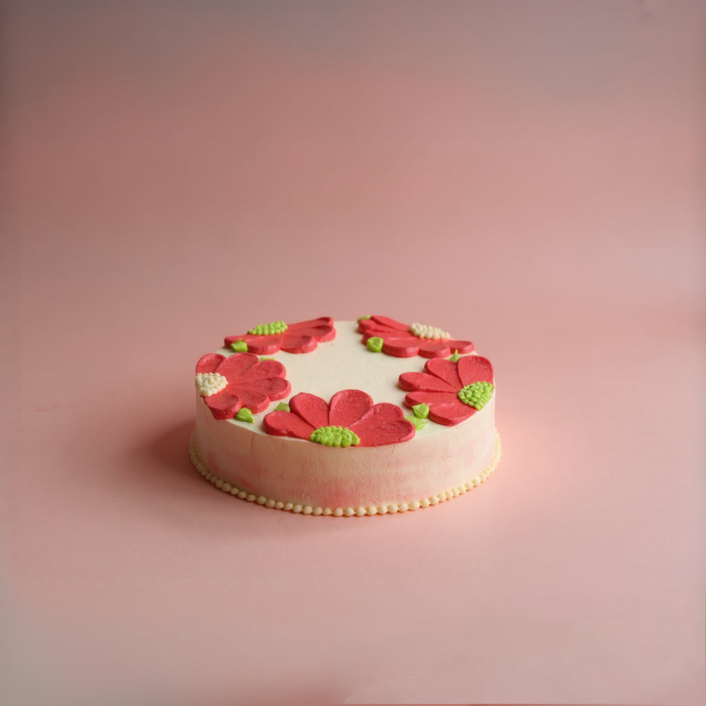 Round cake with red floral decorations on a pink background