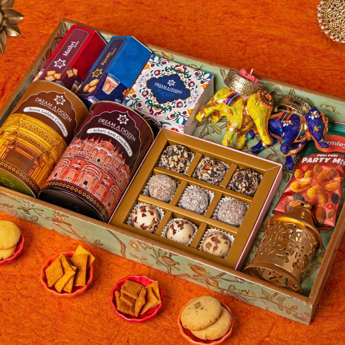 Assorted snacks and candies in a decorative box on an orange surface