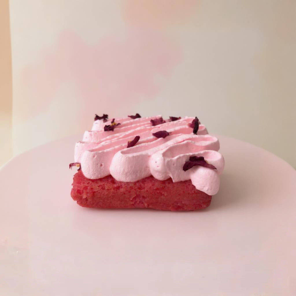 Small pink Rose tres leches with white frosting and chocolate chips on a light pink background