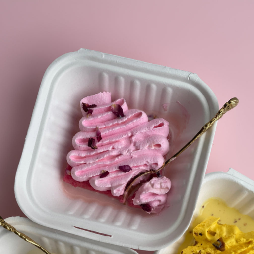 Pink dessert with whipped cream and dried flowers on a light pink background
