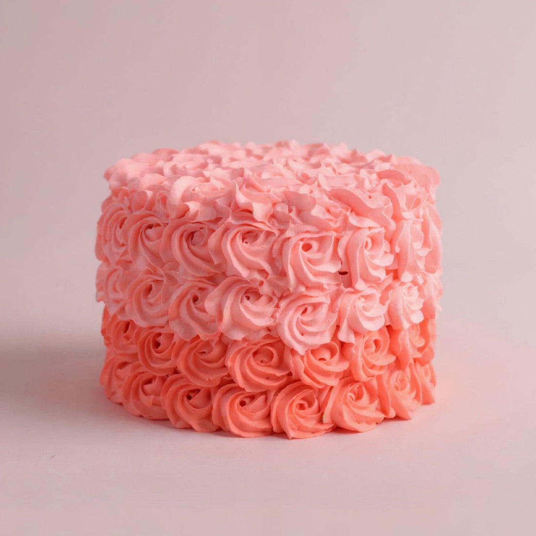 Pink frosted cake with intricate patterns on a light pink background