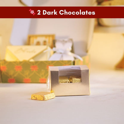 a close up front shot of a simple transparent box with gold borders containing delicious chocolates wrapped in gold foil