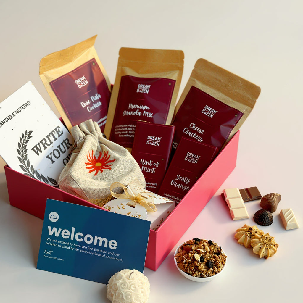 Gourmet gift box with snacks and a 'welcome' card on a decorative surface.